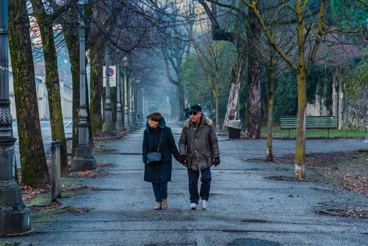 Stariji par u šetnji parkom po sunčanom danu
